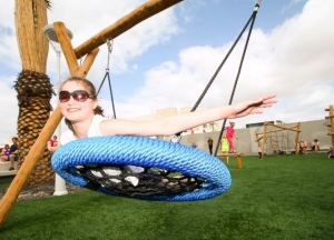 girl-on-swing-safe-playground-artificial-grass-park